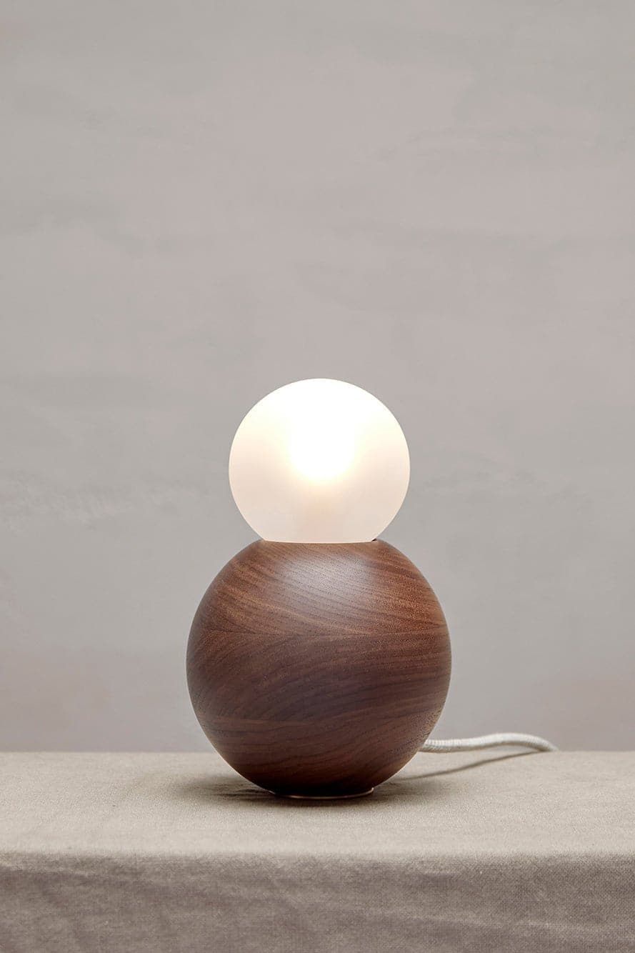 Marz Designs Bright Beads Sphere Table Lamp in Walnut with the light on.