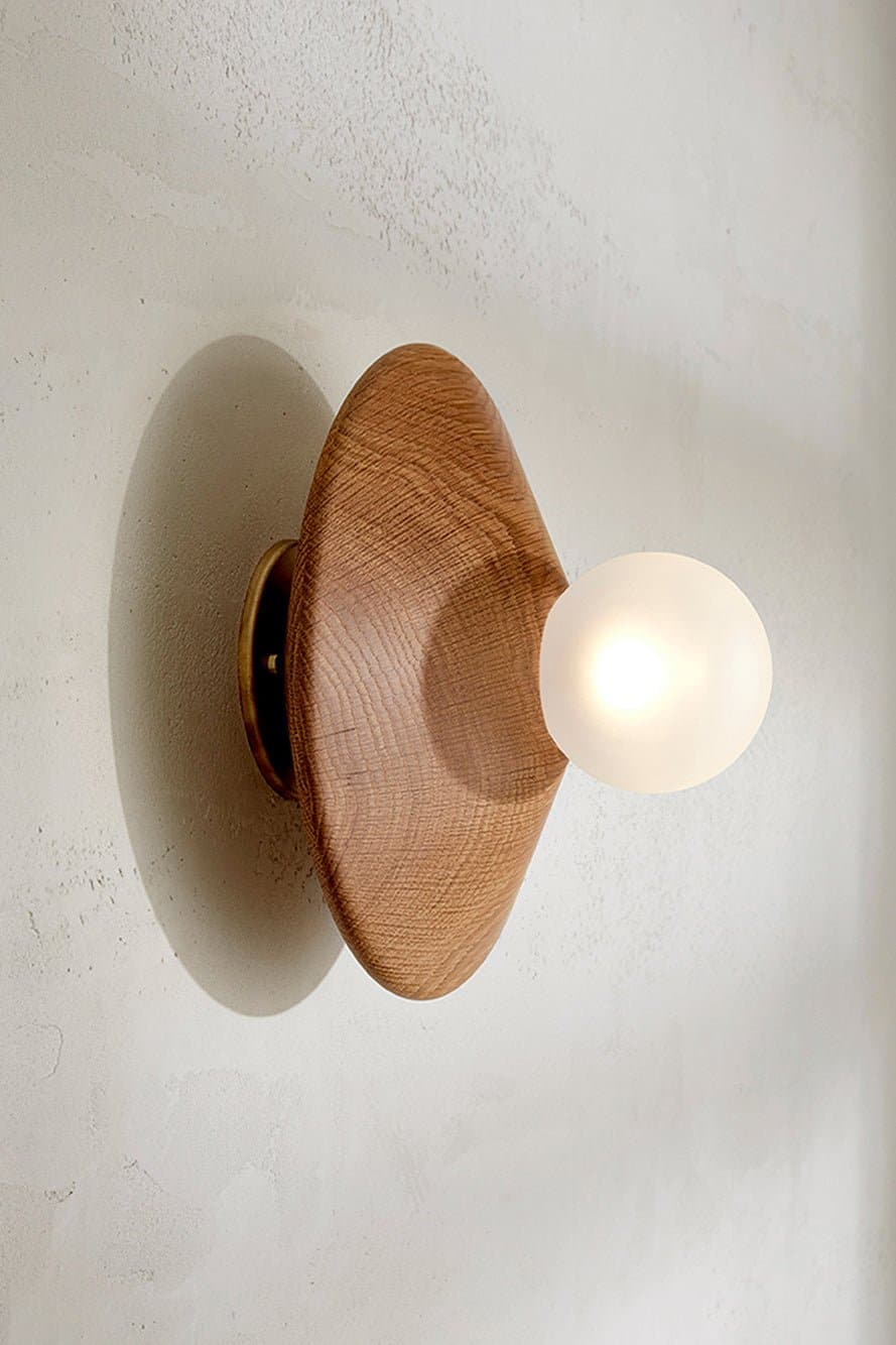 Marz Designs Bright Beads Disc Wall Light in Oak/Brass with the light on.