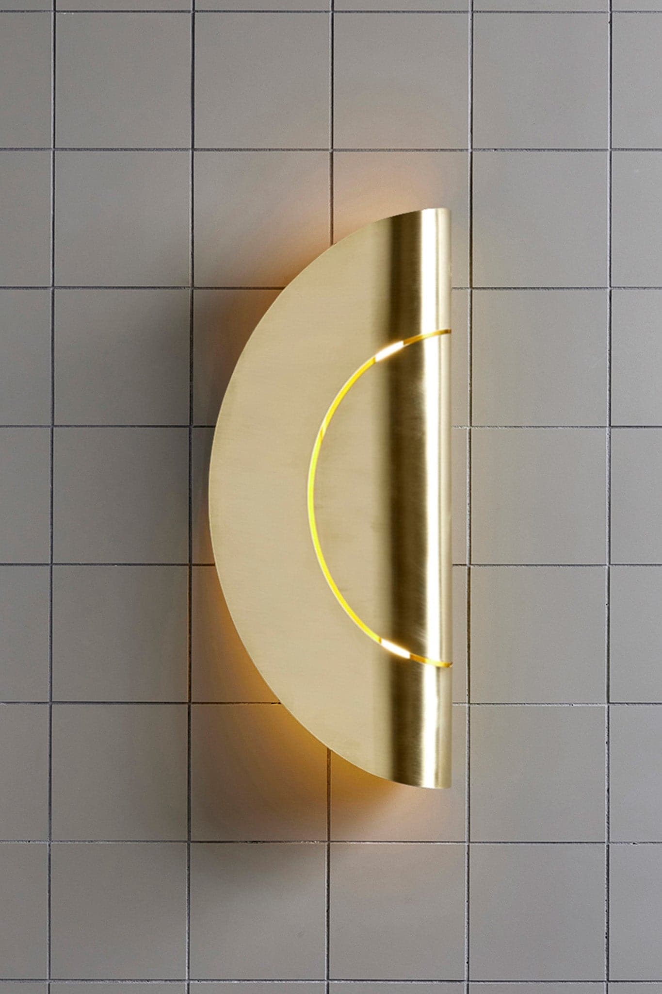Marz Designs Feature Lighting - Furl Circle Wall Light in Natural Brass with the light on.