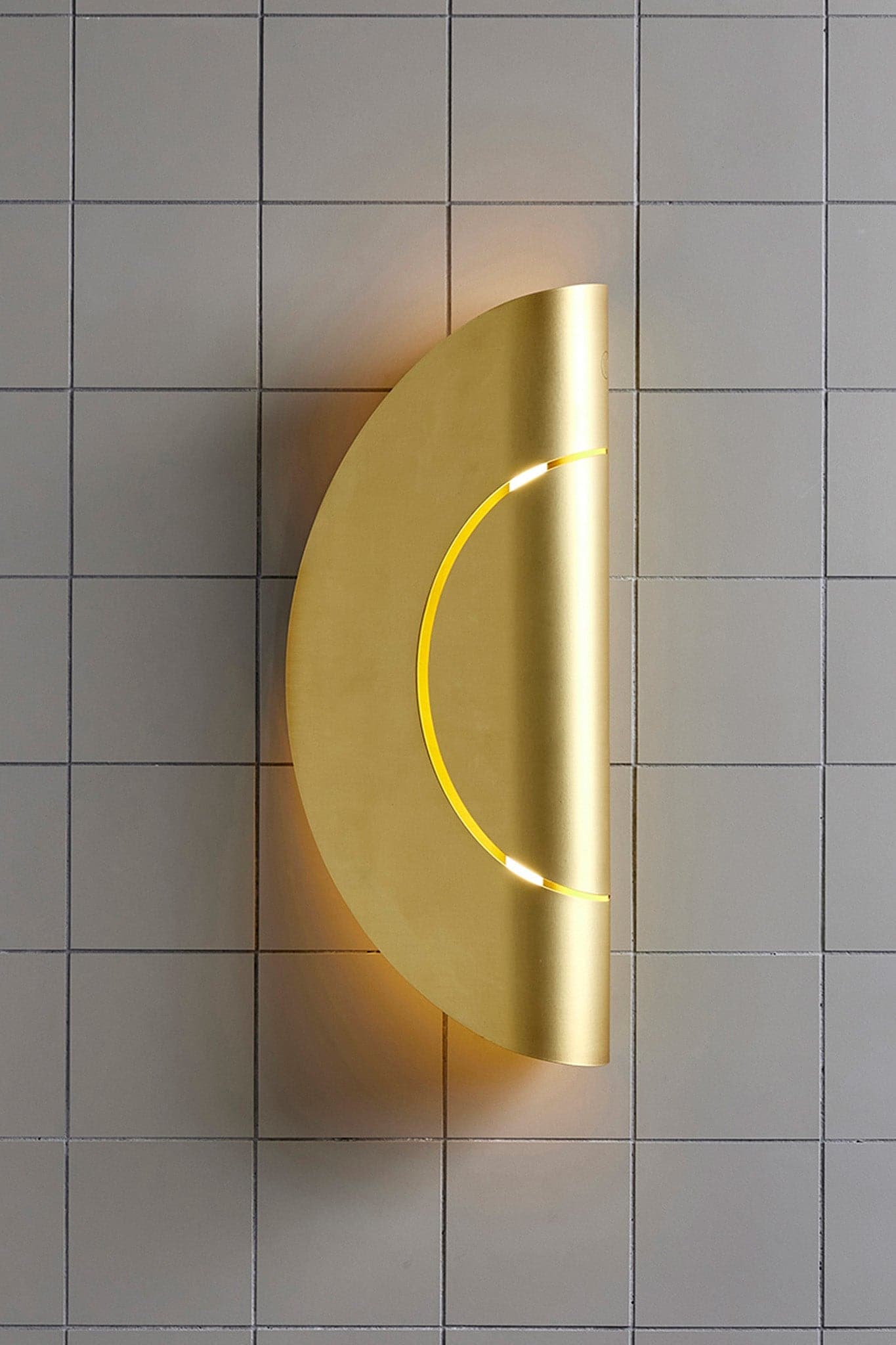 Marz Designs Feature Lighting - Furl Circle Wall Light in Powder Coated Brass with the light on.